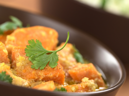 a bowl of colourful sweet potato curry with coriander garnish