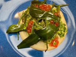 A colourful dish in shades of green and red, cod cheeks in parsley and garlic on potato cream with sea greens and trout roe