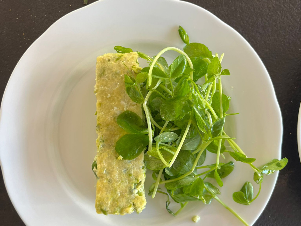 A slice of asparagus pea and parsley bake with bright green watercress salad