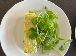 A slice of asparagus pea and parsley bake with bright green watercress salad