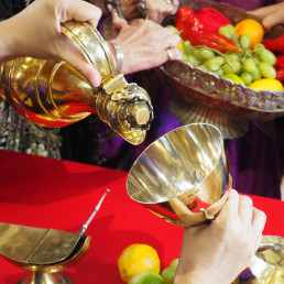 A hedonist spread of food and drink on a red tablecloth with gold decanter and silver goblet